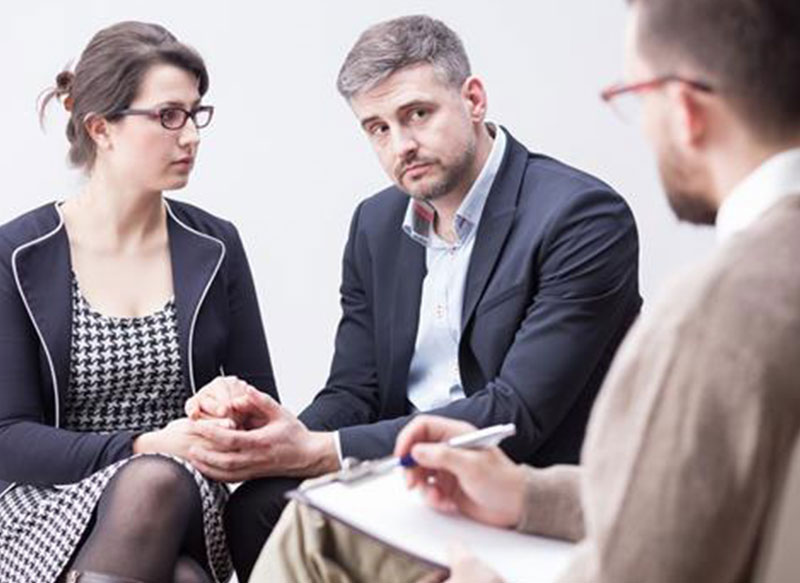 Man and woman in business clothes holding hands and speaking with arbitrator